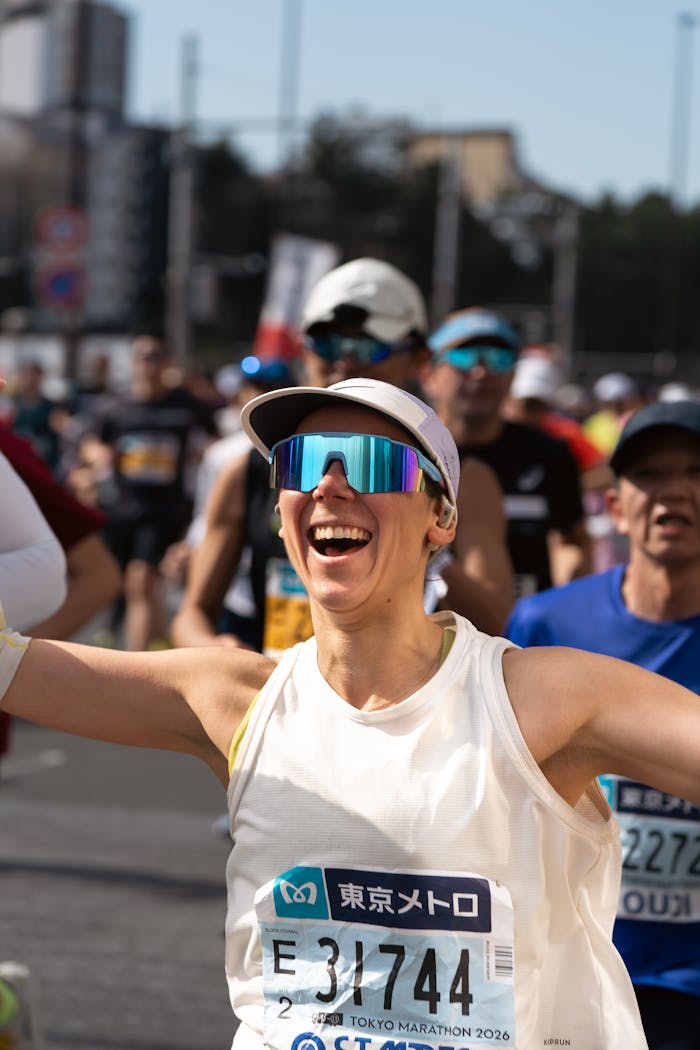 Excited runner celebrates crossing the finish line at the Tokyo Marathon, showcasing enthusiasm and triumph.